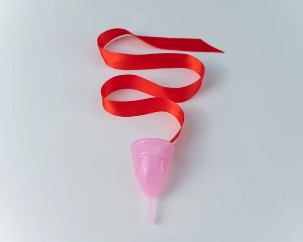 Roze menstruatiecup en rood satijnen lint op een witte achtergrond — Stockfoto