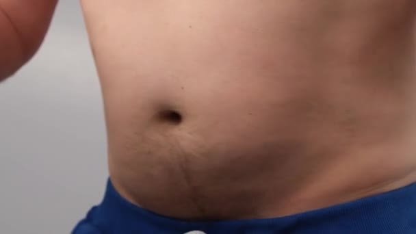 Närbild av en manlig fett skakande mage mot en vit bakgrund. En överviktig man dansar med en naken överkropp. — Stockvideo