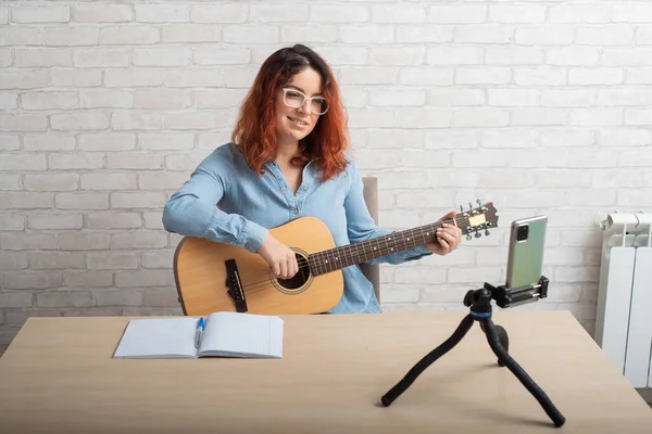 Kaukasierin, die live auf einem Smartphone Gitarre spielt. Das Mädchen führt einen Musikvideoblog — Stockfoto