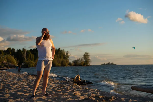 सूर्योदयाच्या वेळी समुद्रकिनारावर टी-शर्ट आणि बॉक्सरमध्ये क्रूर माणसाचे एक विनोदी पोर्ट्रेट — स्टॉक फोटो, इमेज
