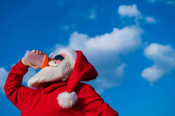 Święty Mikołaj w okularach przeciwsłonecznych pije wodę z shakera na świeżym powietrzu — Zdjęcie stockowe
