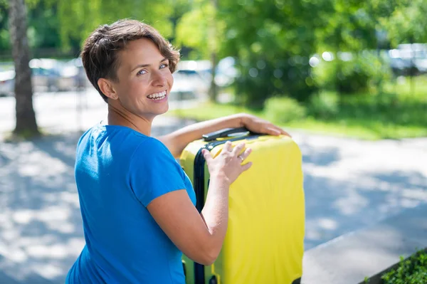 Jonge blanke vrouw buiten met een koffer. — Stockfoto