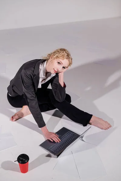 Une ballerine vêtue d'un costume d'affaires pose pour un ordinateur portable et boit du café. Femme flexible travaille à l'ordinateur — Photo