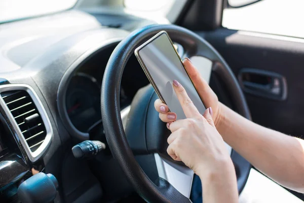 Uma mulher sem rosto usa um telefone celular enquanto dirige um carro. A menina usa a navegação no smartphone — Fotografia de Stock