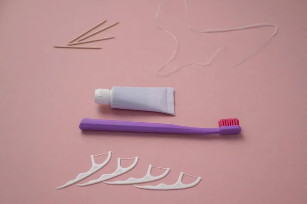 Producto personal de higiene bucal sobre fondo rosa. Cepillo de dientes tubo de pasta de dientes palillo de dientes y hilo dental. Acostado. Copiar espacio — Foto de Stock
