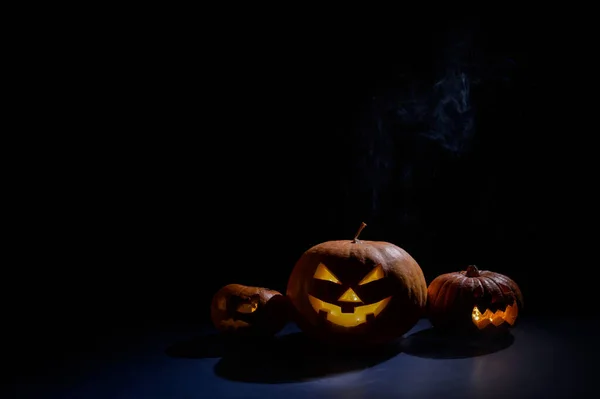 Dýně s vyřezávanými grimasami a svíčkami ve tmě na Halloween. Jack o latern in smoke. — Stock fotografie