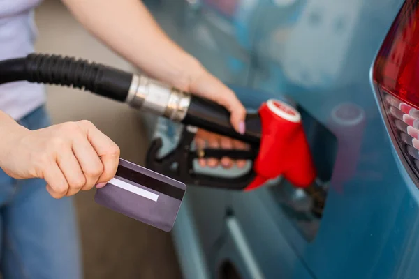 Kobieta napełnia samochód benzyną na stacji benzynowej i trzyma kartę kredytową. — Zdjęcie stockowe