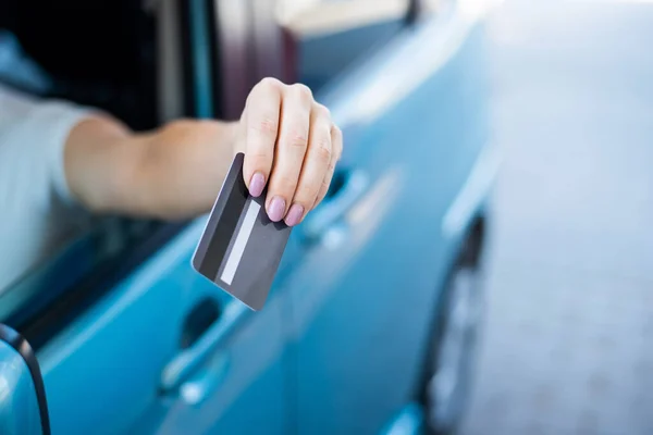 Uma mulher paga com um cartão de crédito enquanto reabastece um carro — Fotografia de Stock