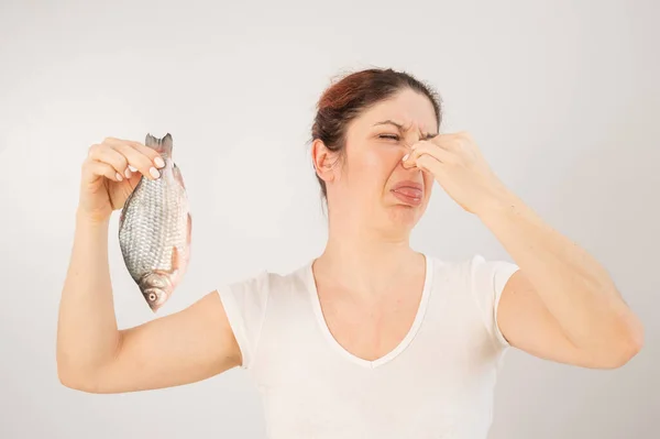 Vit kvinna motsätter sig den vidriga doften av fisk. En metafor för kvinnors hälsa och intim hygien. — Stockfoto