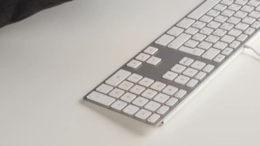 Yüzü olmayan bir kadın hamburger yiyor ve klavyeye ketçap döküyor.