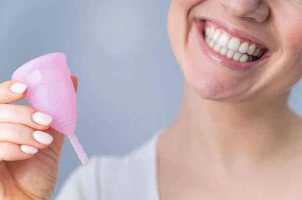 Ritratto ravvicinato di una donna caucasica sorridente che tiene una coppetta mestruale rosa su sfondo bianco. Alternativa a assorbenti e assorbenti nei giorni critici. — Foto Stock