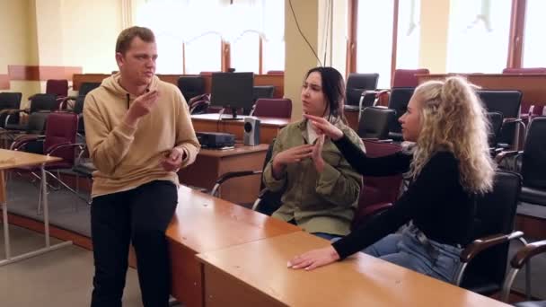 Tres estudiantes sordos y sordos se comunican en lenguaje de señas en un aula universitaria. — Vídeo de stock