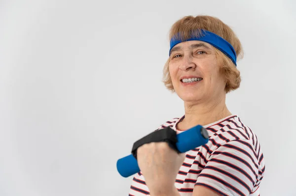 Fröhliche alte Frau bei Fitnessübungen mit Kurzhanteln auf weißem Hintergrund. Ältere Dame macht Fitness, um ihre Gesundheit zu erhalten. — Stockfoto