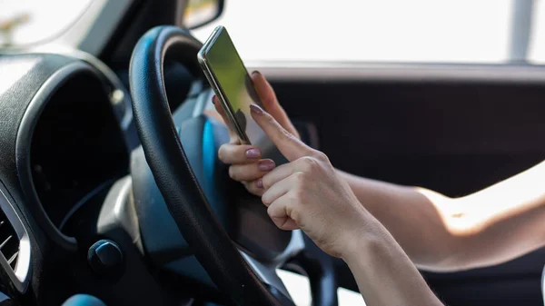 Uma mulher sem rosto usa um telefone celular enquanto dirige um carro. A menina usa a navegação no smartphone — Fotografia de Stock