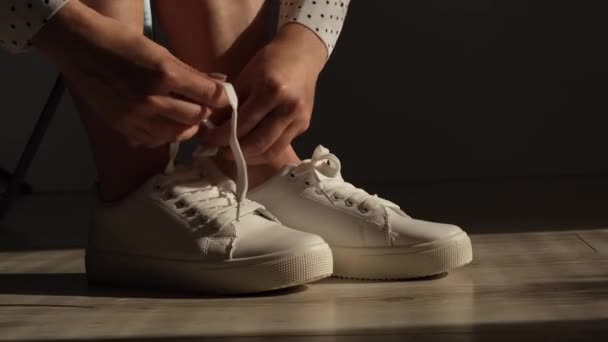 Vrouw zet nieuwe witte lederen sneakers op — Stockvideo