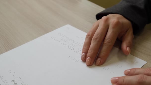 Wanita close-up membaca teks untuk orang buta. Tangan di atas kertas dengan kode braille. — Stok Video