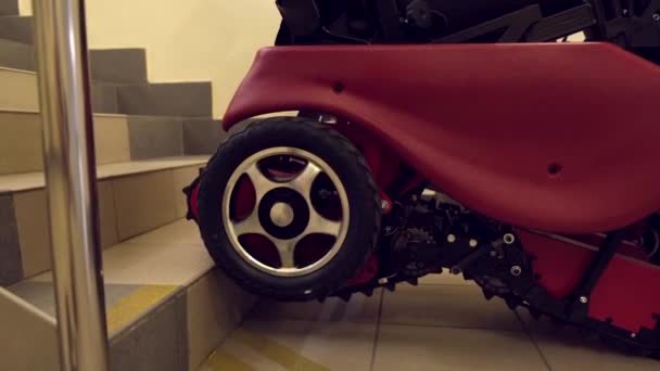 Gros plan d'un fauteuil roulant électrique monte une échelle sur une chenille. — Video