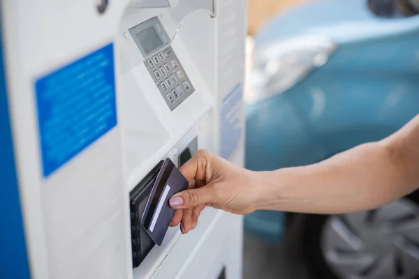 Uma mulher enche seu carro com gasolina em um posto de gasolina self-service e paga com um cartão de crédito em uma máquina — Fotografia de Stock