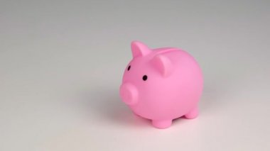 Yüzsüz beyaz kadın küçük bir kalbi beyaz arka planda pembe bir domuz kumbarasına çeviriyor. Aşk tasarruf kavramı