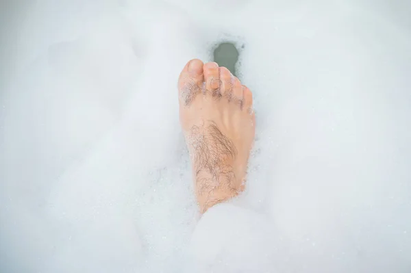한 남자가 쉬는 목욕을 하고 있는 이상 한 사진입니다. 거품 목욕을 하는 남성 발의 근접 사진 — 스톡 사진