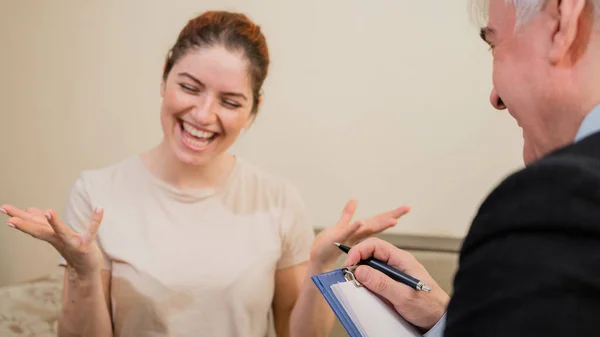 여성 환자와 상담중인 성숙 한 회색 머리의 남성 심리 치료사. 심리 상담을 받고 있는 코카서스 여성에게 미소짓는 모습. — 스톡 사진