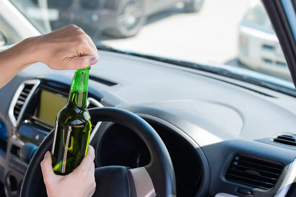 Yüzsüz bir kadın araba sürerken bir şişe bira açar. Kanunları çiğnemek ve araba kullanırken alkol içmek. — Stok fotoğraf