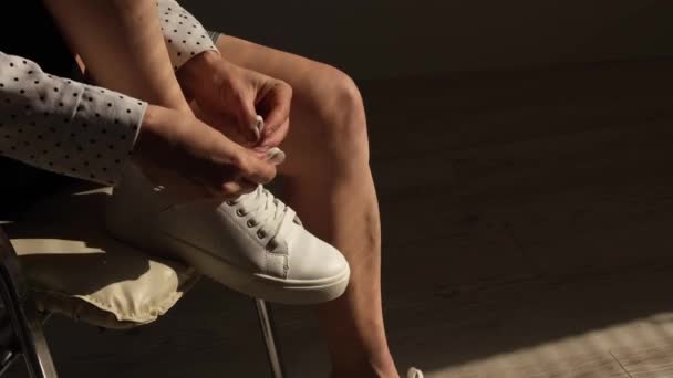 Vrouw zet nieuwe witte lederen sneakers op — Stockvideo