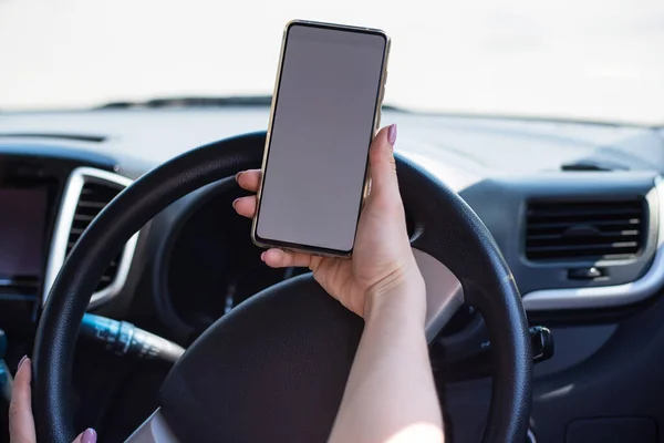 Uma mulher sem rosto usa um telefone celular enquanto dirige um carro. A menina usa a navegação no smartphone — Fotografia de Stock