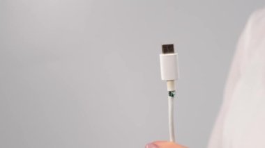 Yakın plan kadın elinde yırtık telefon şarj aleti tip C kablosu tutuyor..