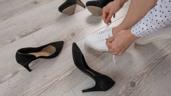Bir kadın yüksek topuklu ayakkabı yerine spor ayakkabıları seçer. Spor ayakkabı ya da ayakkabı.