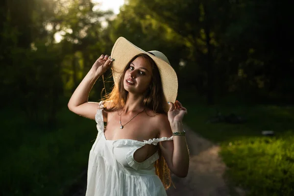 Mulher branca bonita em um vestido branco e chapéu de palha na floresta — Fotografia de Stock