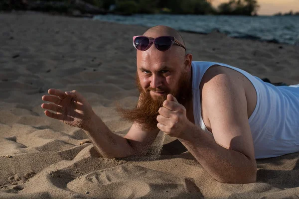 Un ritratto umoristico di un uomo brutale in maglietta e pugili sulla spiaggia al tramonto — Foto Stock