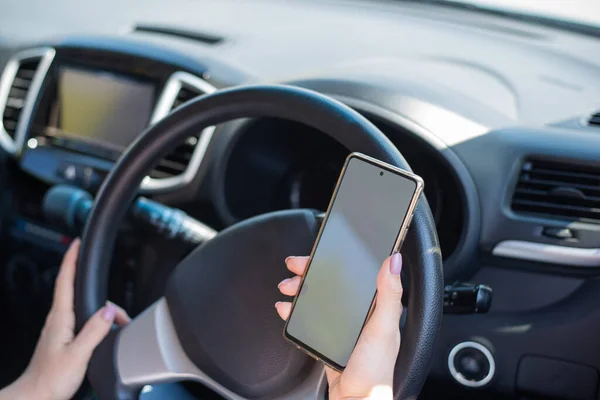 Uma mulher sem rosto usa um telefone celular enquanto dirige um carro. A menina usa a navegação no smartphone — Fotografia de Stock