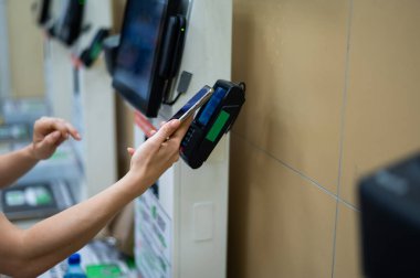 Bir kadın kasada akıllı telefonuyla ödeme yapıyor..
