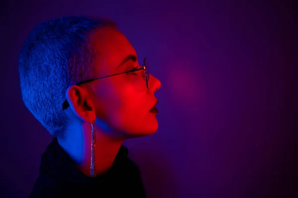 Porträtt av vacker ung kvinna med kort hår bär glasögon i neon ljus — Stockfoto
