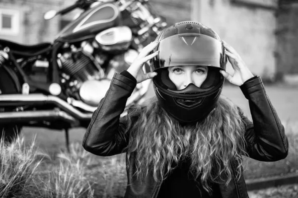 Mulher ruiva encaracolada num capacete perto de uma mota. Monocromático. — Fotografia de Stock