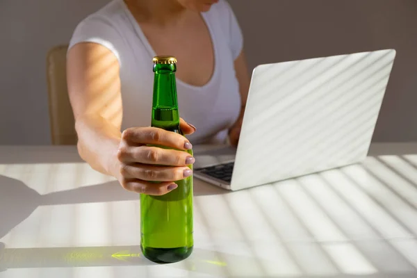 Femme blanche travaille à un ordinateur portable et boit de la bière à partir d'une bouteille en verre — Photo