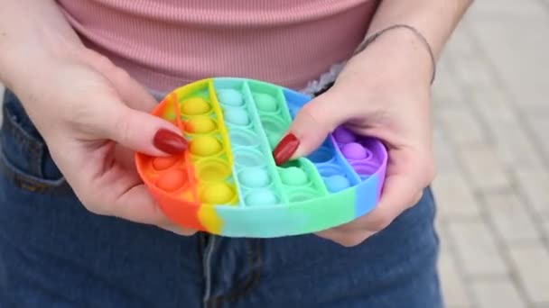 Mujer jugando juguete anti-estrés pop it. Primer plano de las manos femeninas burbujas estallando — Vídeos de Stock
