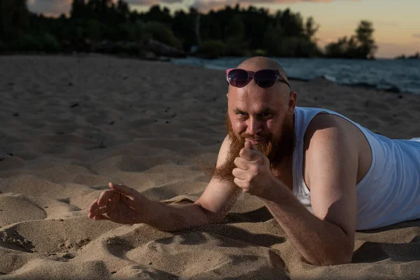 Un ritratto umoristico di un uomo brutale in maglietta e pugili sulla spiaggia al tramonto — Foto Stock