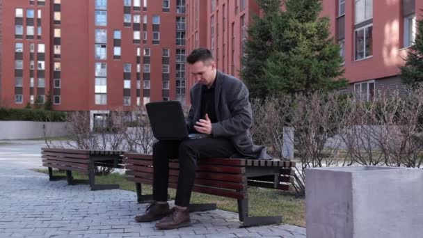 El hombre que escribe en el portátil se pone nervioso y lo rompe al aire libre. Movimiento lento — Vídeos de Stock