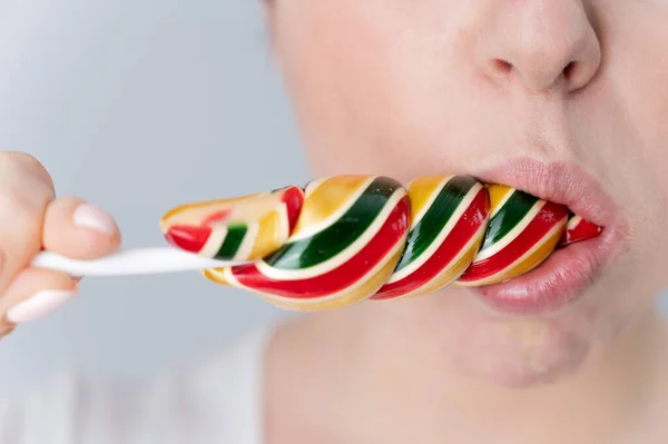 Close-up portrait of a woman sucking a long lollipop against a white background. Blowjob simulation — Photo