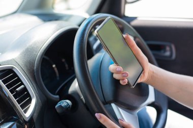 Yüzü olmayan bir kadın araba sürerken cep telefonu kullanır. Kız akıllı telefondaki navigasyonu kullanıyor.