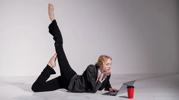 Barefoot Ballerina kledd i dress poserer for en laptop og drikker kaffe. Fleksibel kvinne jobber på datamaskinen – stockfoto