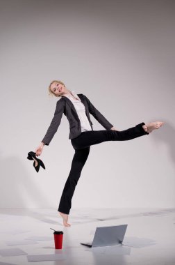 İş elbisesi giymiş çıplak ayaklı balerin dizüstü bilgisayara poz veriyor ve kahve içiyor. Bilgisayar başında esnek bir kadın çalışıyor.