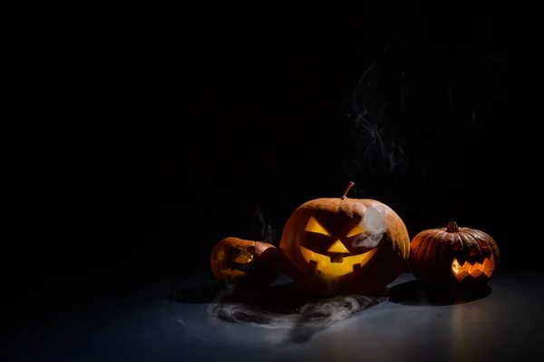 Dýně s vyřezávanými grimasami a svíčkami ve tmě na Halloween. Jack o latern in smoke. — Stock fotografie