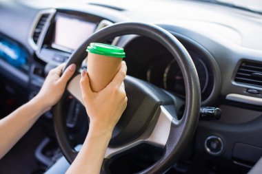 Meçhul bir kadın araba sürerken el işi bardakta kahve içiyor. Almak için sıcak bir tonik al