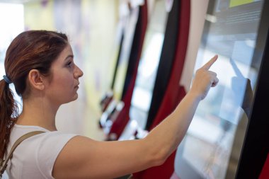 Kadın alışveriş merkezinde dokunmatik danışma masası kullanıyor.