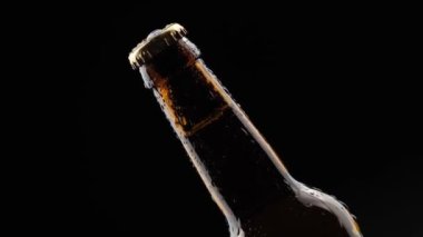 Siyah arka planda dönen cam bira şişesi.