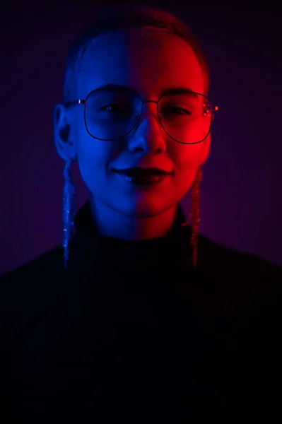 Porträt einer schönen jungen Frau mit kurzen Haaren, die eine Brille im Neonlicht trägt — Stockfoto