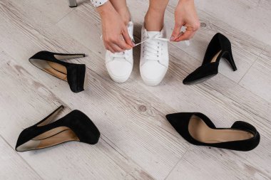 Bir kadın yüksek topuklu ayakkabı yerine spor ayakkabıları seçer. Spor ayakkabı ya da ayakkabı.